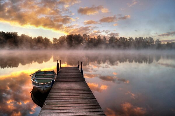 Bridge and boat on the lake in the morning fog