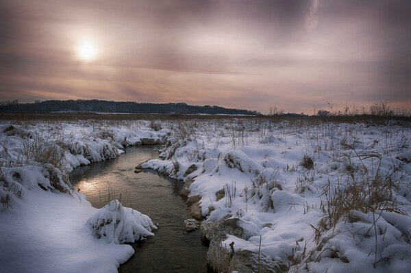 Winterfeld. Fluss zwischen Schneeverwehungen