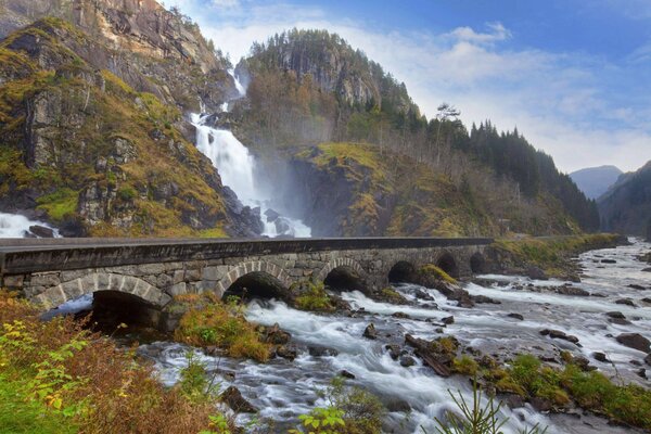 Puente de piedra cerca de una cascada de montaña