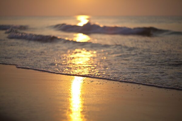 All alba, le onde del mare riflettono i raggi del sole